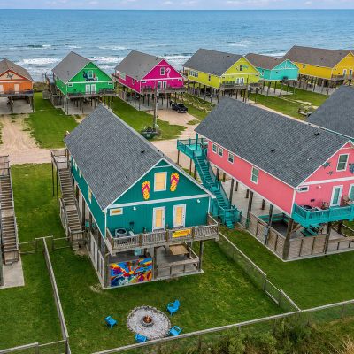 Aerial view of colorful beachfront vacation rental homes on stilts in Crystal Beach Texas at sunset